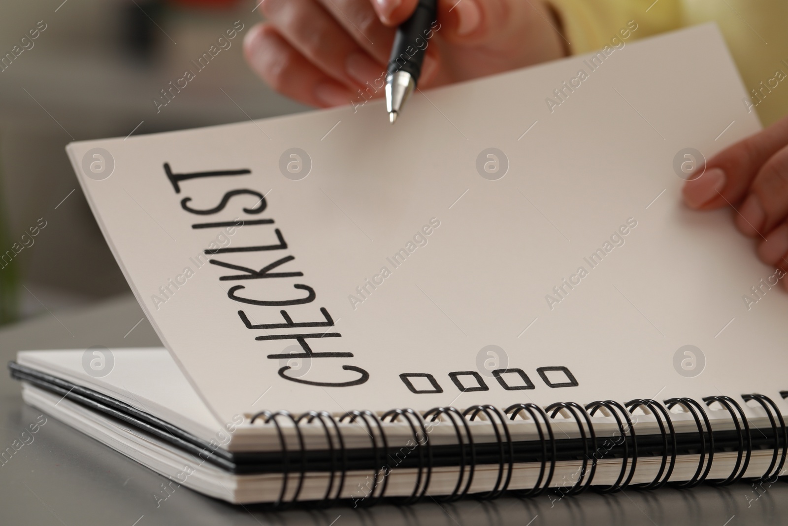 Photo of Woman filling Checklist at grey table, closeup