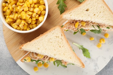 Delicious sandwiches with tuna, corn and greens on light grey table, top view