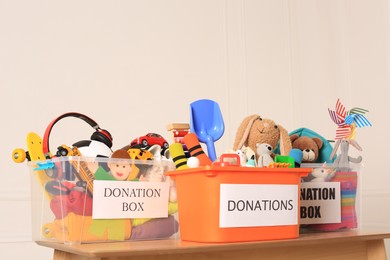 Photo of Donation boxes with different child toys on wooden table