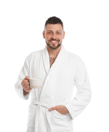 Handsome man in bathrobe with cup of coffee on white background