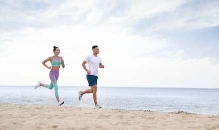 Photo of Couple running together on beach, space for text. Body training