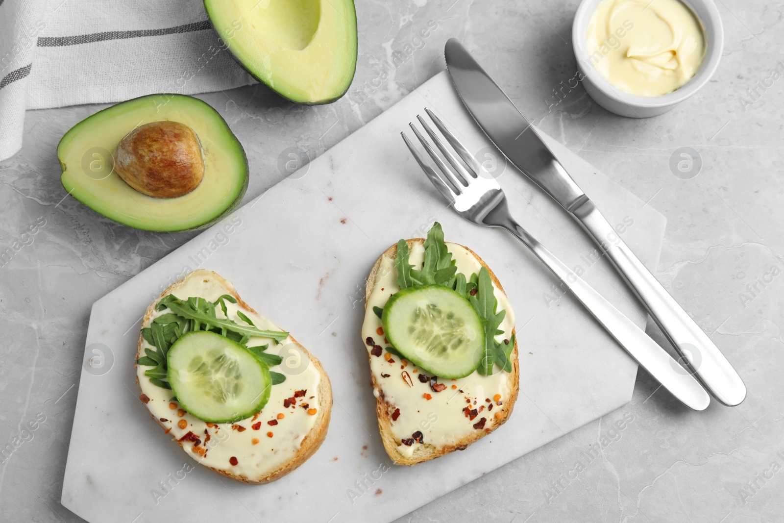 Photo of Slices of bread with spread and cucumber on grey marble table, flat lay