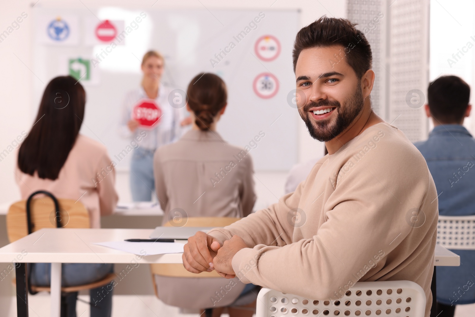 Photo of Happy man at desk in class during lesson in driving school