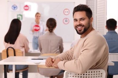 Photo of Happy man at desk in class during lesson in driving school