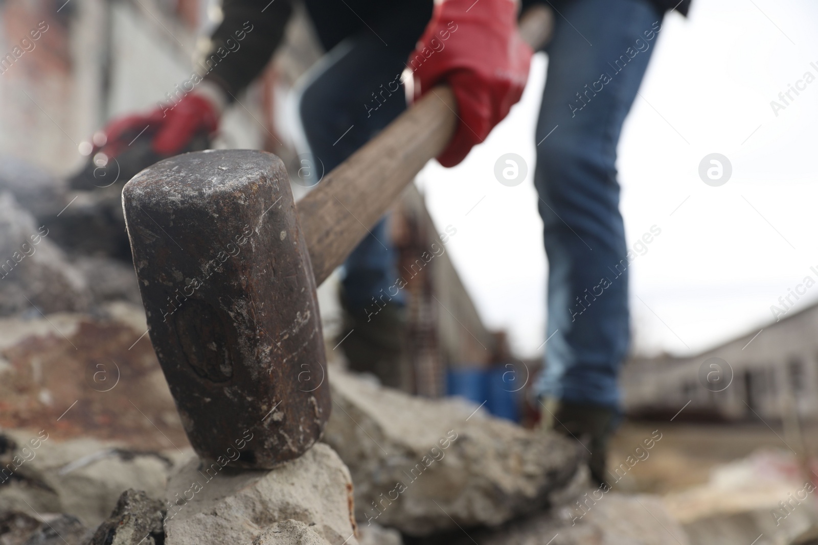 Photo of Man breaking stones with sledgehammer outdoors, selective focus