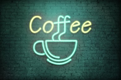 Glowing neon sign with cup and word Coffee on brick wall