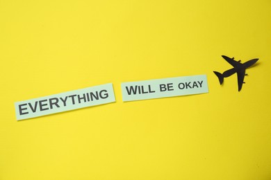 Photo of Cards with phrase Everything Will Be Okay and paper cutout of plane on yellow background, flat lay