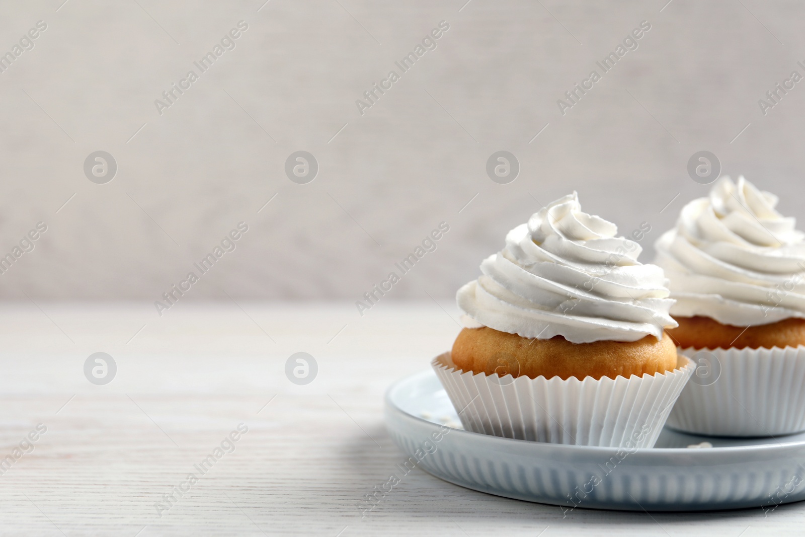 Photo of Delicious cupcakes with cream on white wooden table. Space for text