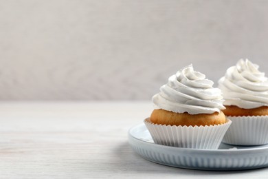 Photo of Delicious cupcakes with cream on white wooden table. Space for text