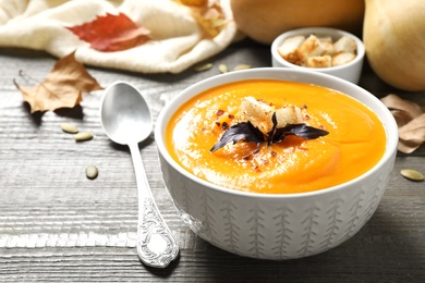 Delicious pumpkin soup in bowl on wooden table