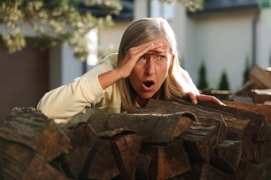 Photo of Concept of private life. Curious senior woman spying on neighbours over firewood outdoors