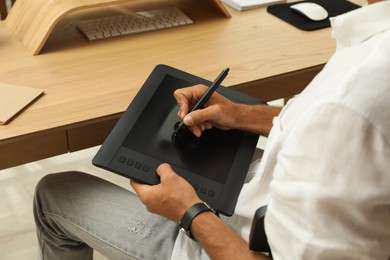 Professional retoucher working on graphic tablet at desk, closeup