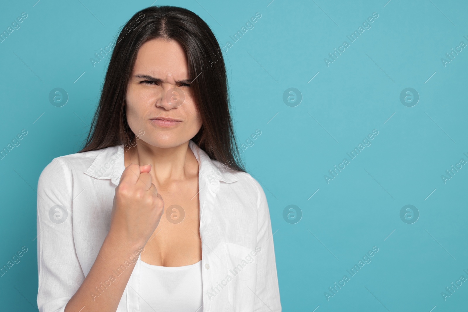 Photo of Aggressive young woman on turquoise background, space for text