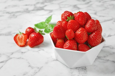 Bowl with ripe strawberries on marble background