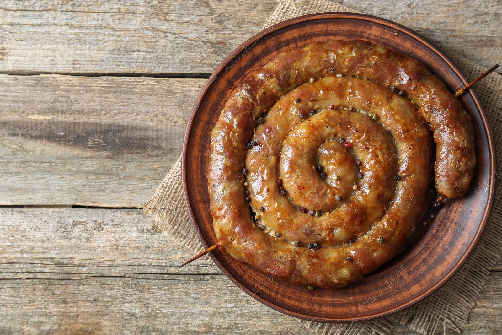 Photo of Plate with tasty homemade sausages on wooden table, top view. Space for text