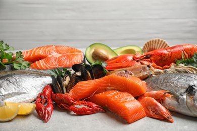Photo of Fresh fish and different seafood on light grey table, closeup