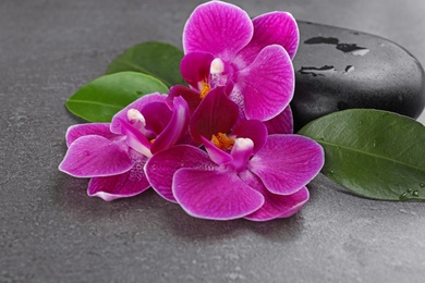 Photo of Spa stones and orchid flowers on grey background