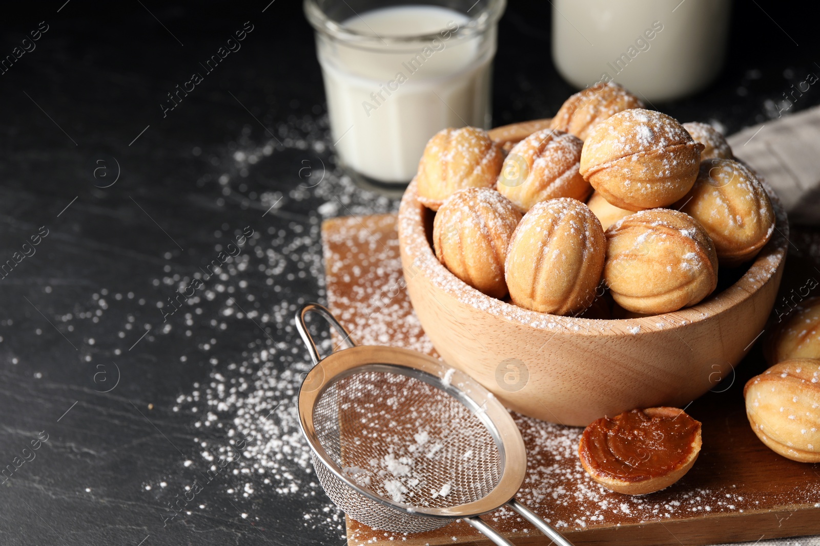 Photo of Homemade walnut shaped cookies with boiled condensed milk on black table, space for text