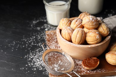 Photo of Homemade walnut shaped cookies with boiled condensed milk on black table, space for text