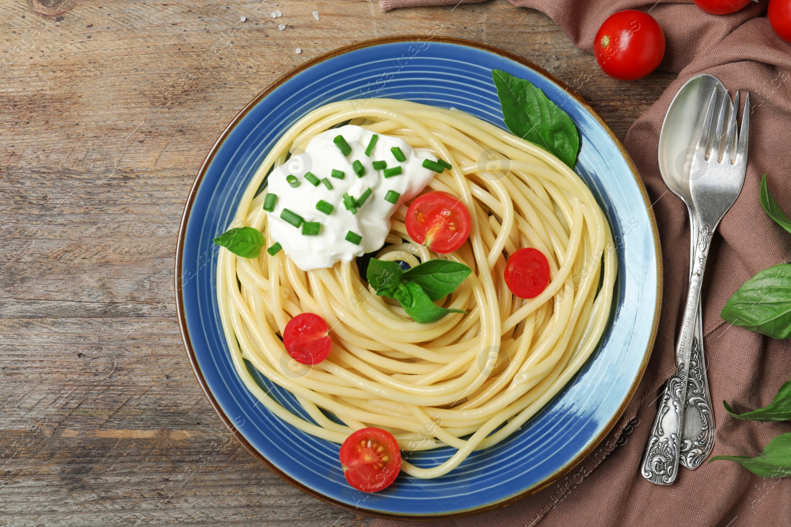 Photo of Delicious spaghetti with sour cream served on wooden table, flat lay