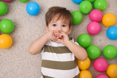 Cute little child playing with balls on floor, top view