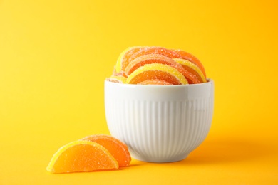 Photo of Yummy jelly candies in bowl on orange background