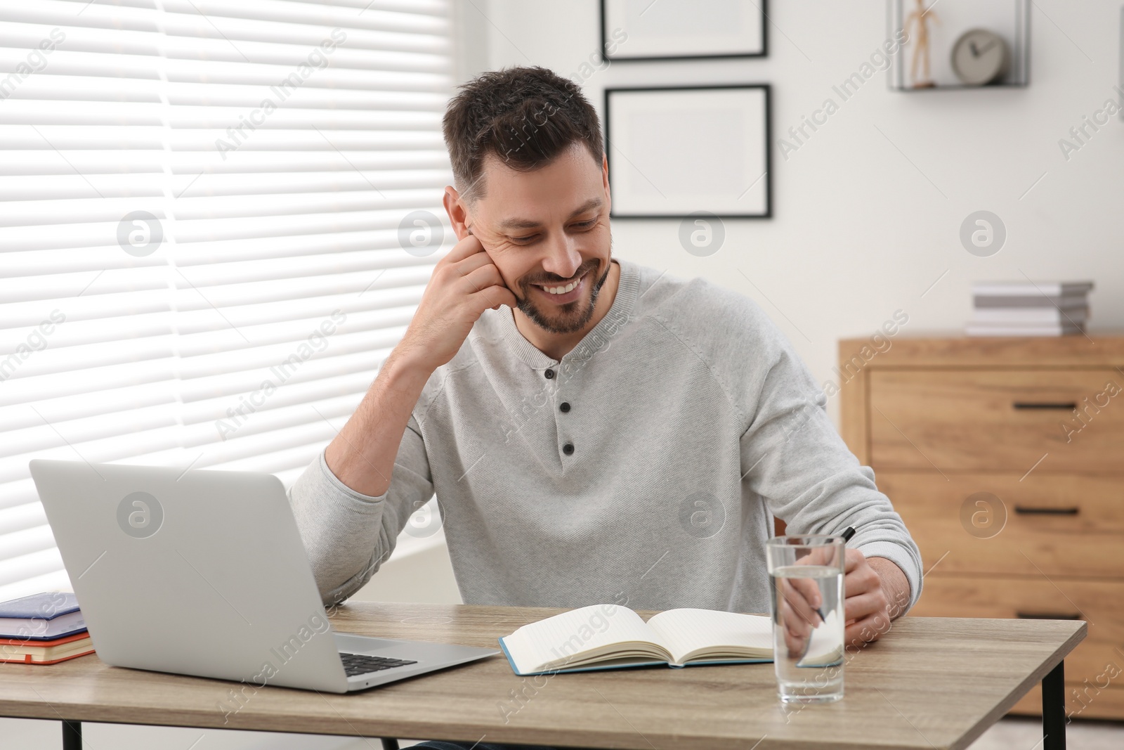 Photo of Online translation course. Man writing near laptop at home