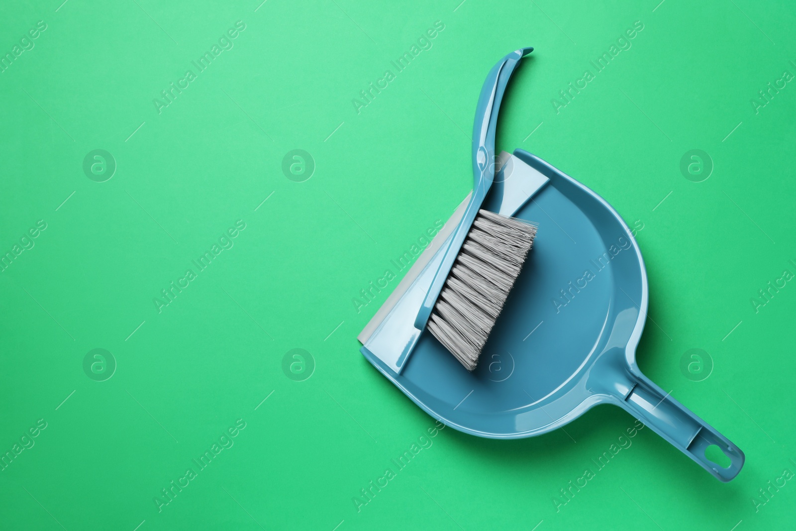 Photo of Plastic hand broom and scoop on green background, flat lay. Space for text