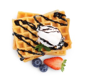 Tasty Belgian waffles with ice cream, berries and chocolate syrup on white background, top view