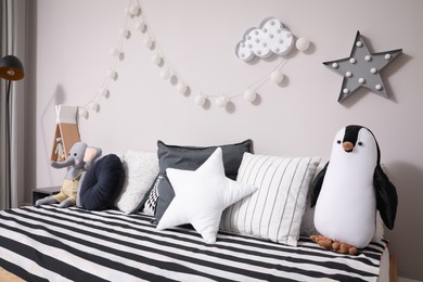 Photo of Comfortable bed with pillows and toys indoors. Cute kids room interior