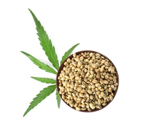 Photo of Bowl of hemp seeds with green leaf on white background, top view