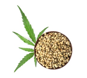 Bowl of hemp seeds with green leaf on white background, top view