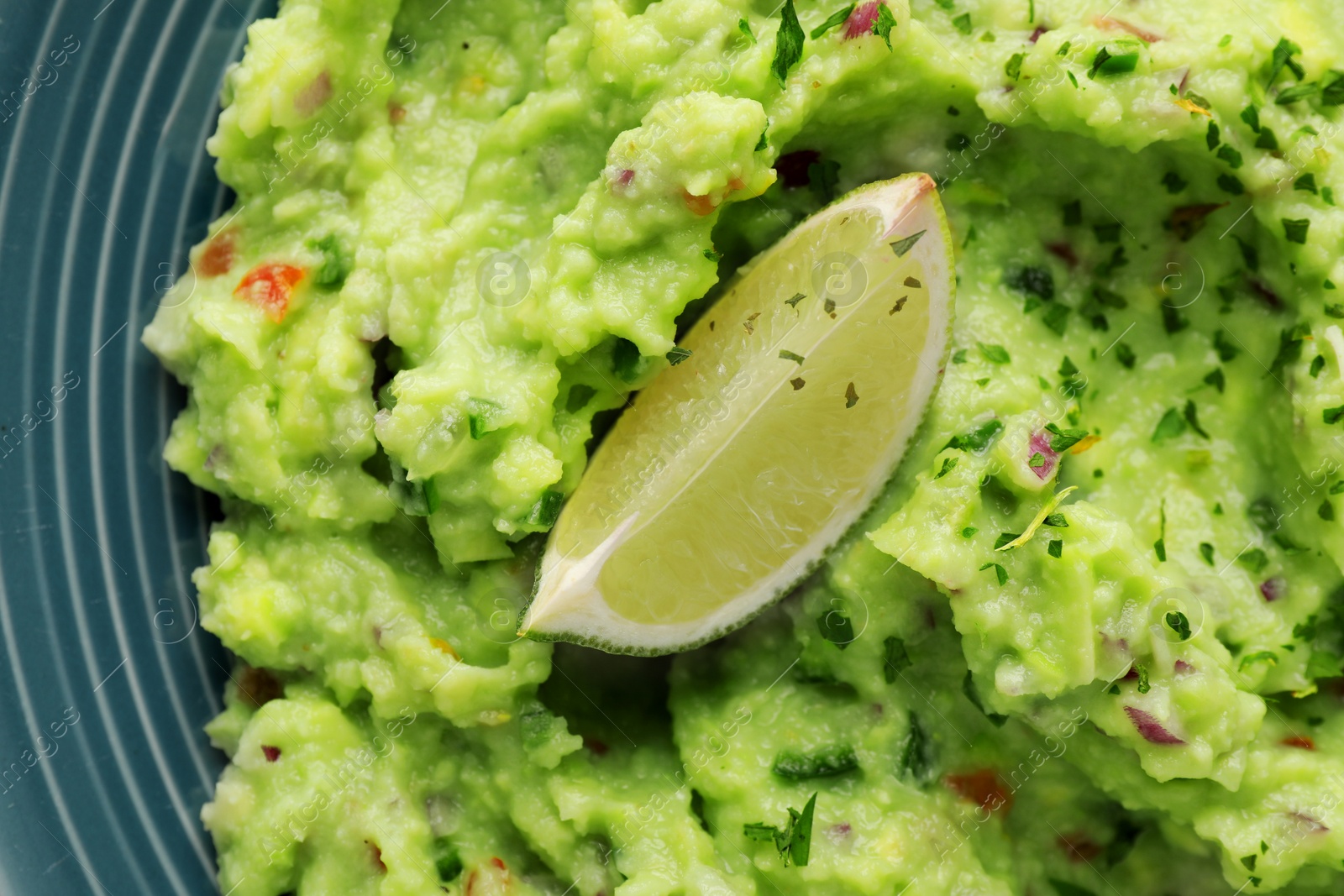 Photo of Delicious guacamole served with lime on plate, top view