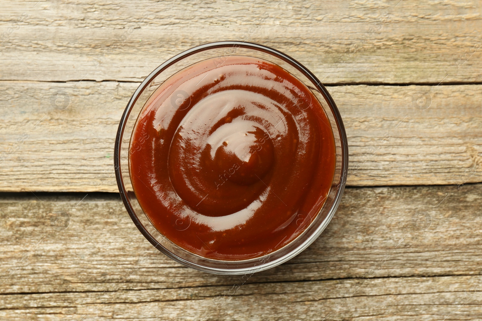 Photo of Tasty barbeque sauce in bowl on wooden table, top view