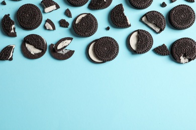 Photo of Tasty chocolate cookies with cream on color background, flat lay. Space for text