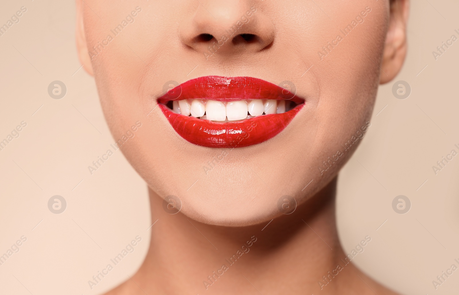 Photo of Beautiful young woman with red glossy lips on color background, closeup