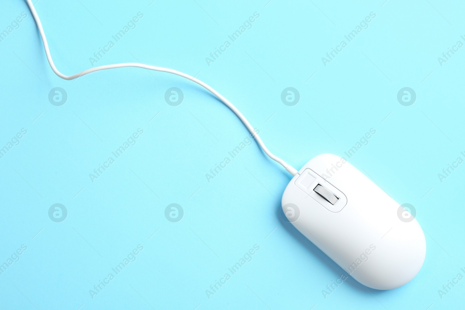 Photo of Modern wired mouse on light blue background, top view