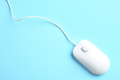 Modern wired mouse on light blue background, top view