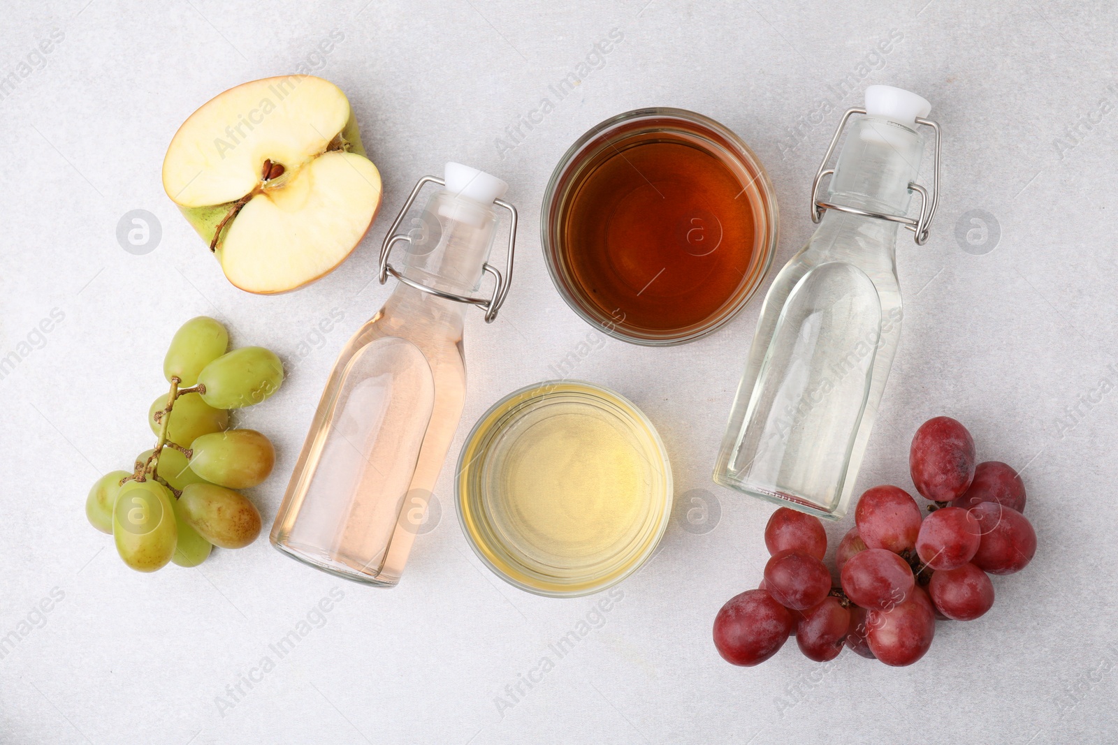 Photo of Different types of vinegar and ingredients on light table, flat lay