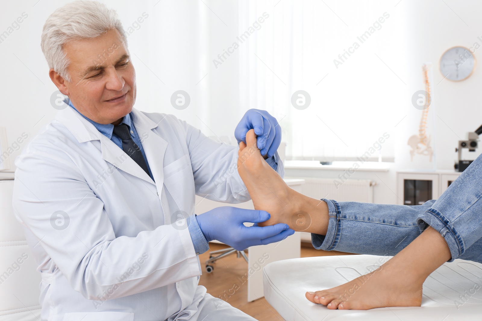 Photo of Male orthopedist checking patient's foot in clinic