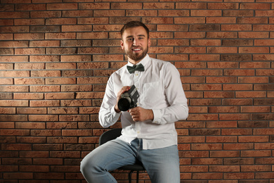 Young man with vintage video camera near brick wall