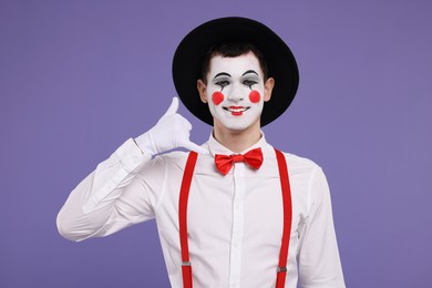 Photo of Funny mime artist showing call me gesture on purple background