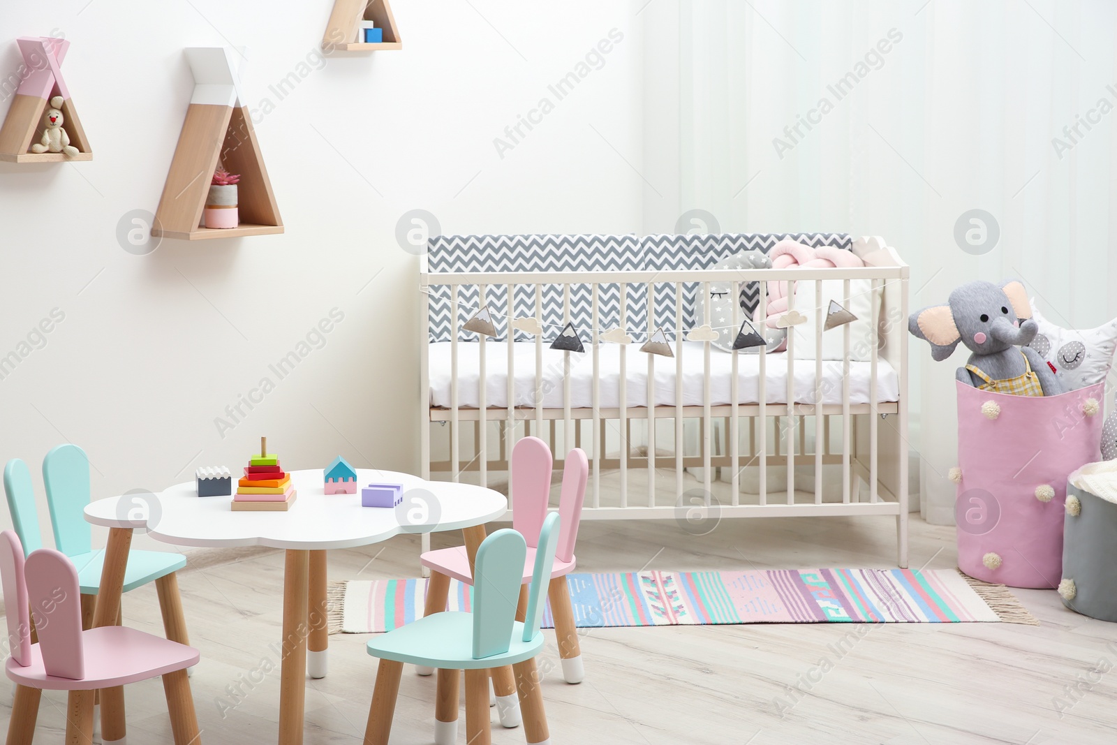 Photo of Cute baby room interior with cot and little table