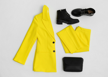 Stylish ankle boots, handbag and yellow office suit on white background, top view