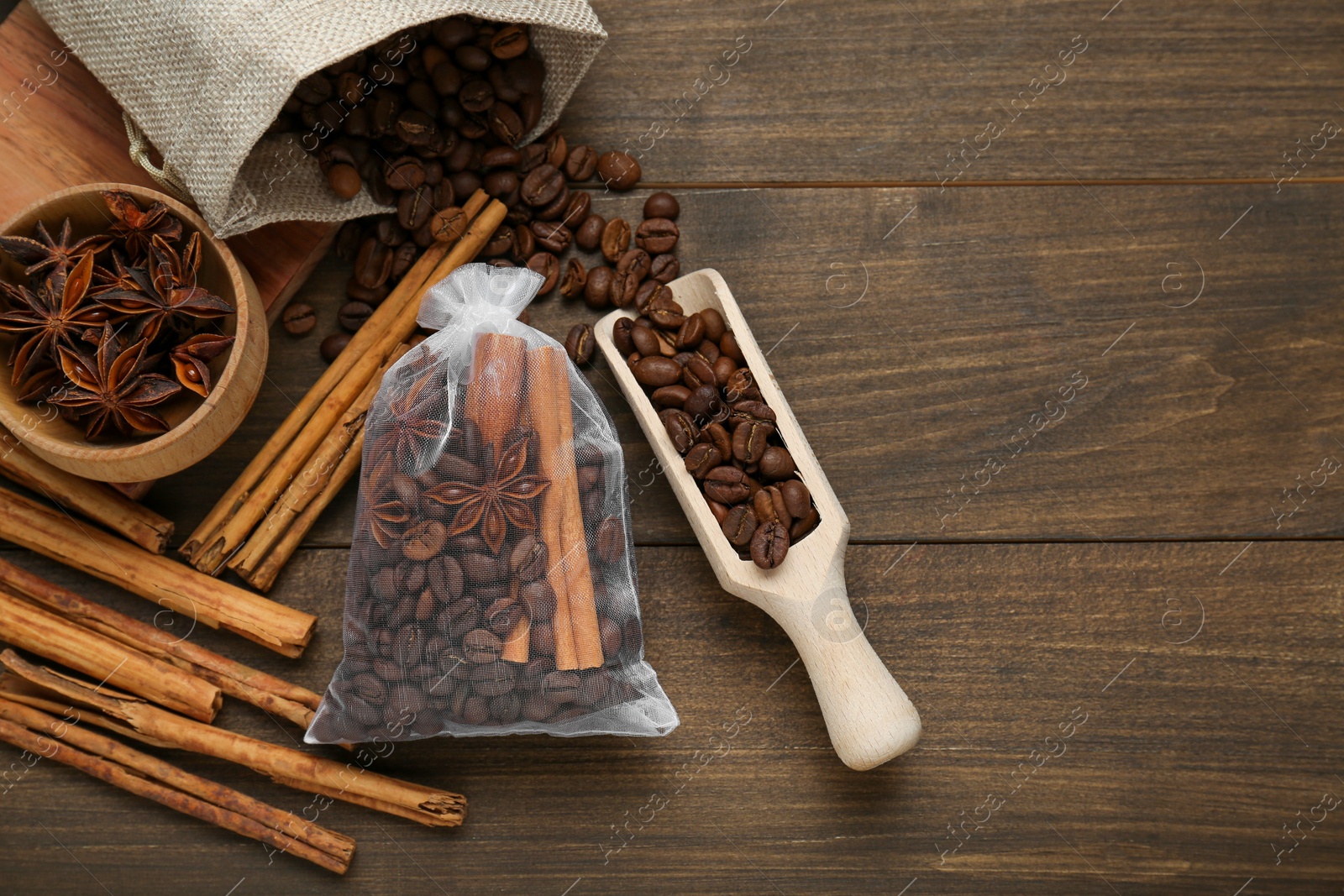 Photo of Scented sachet with coffee beans, anise and cinnamon on wooden table, flat lay. Space for text