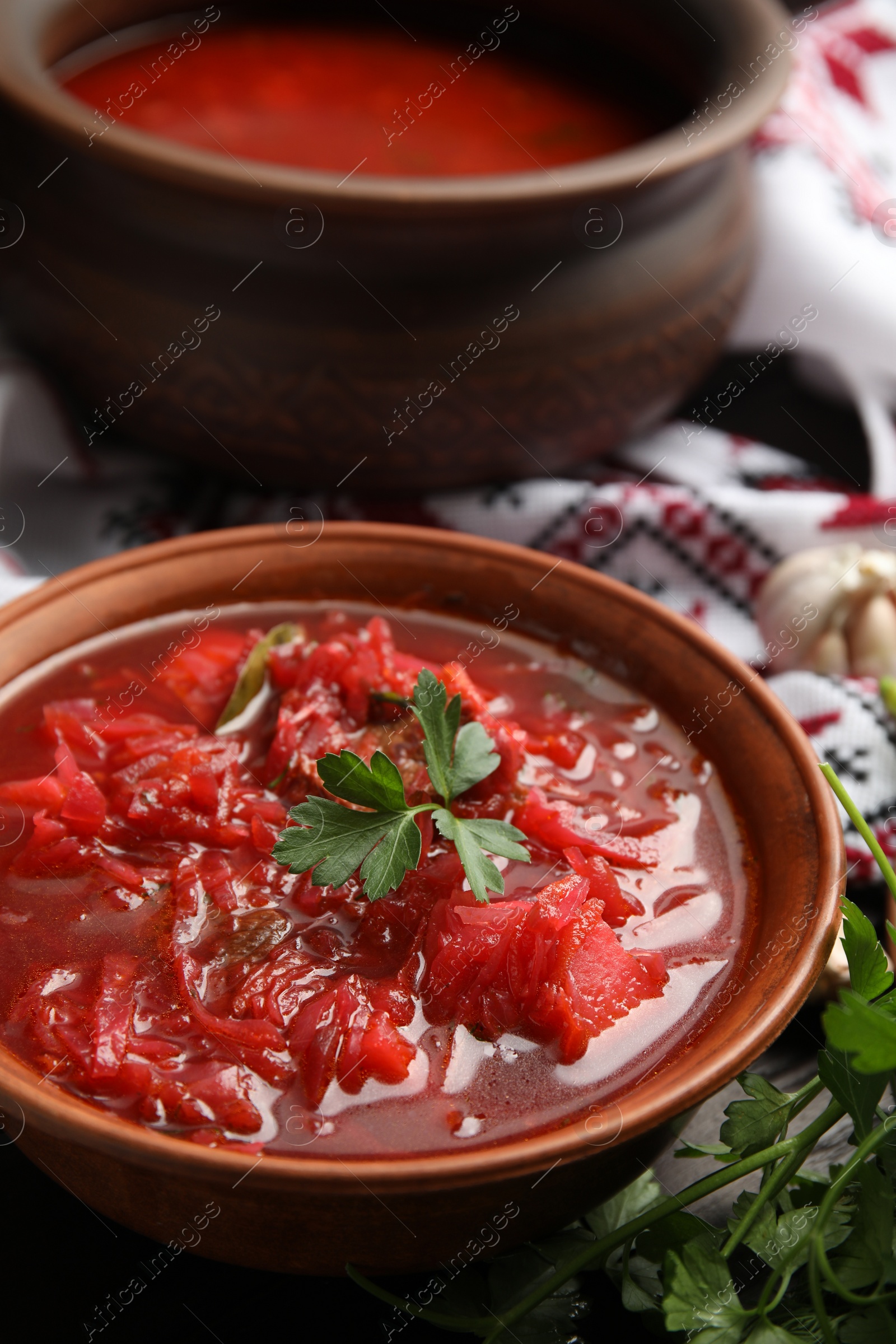 Photo of Stylish brown clay bowl with Ukrainian borsch served on table