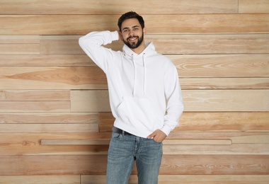 Photo of Portrait of young man in sweater at wooden wall. Mock up for design