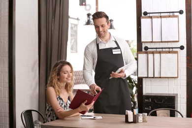 Photo of Young waiter taking order from client in restaurant