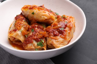 Photo of Delicious stuffed cabbage rolls cooked with homemade tomato sauce on black table, closeup