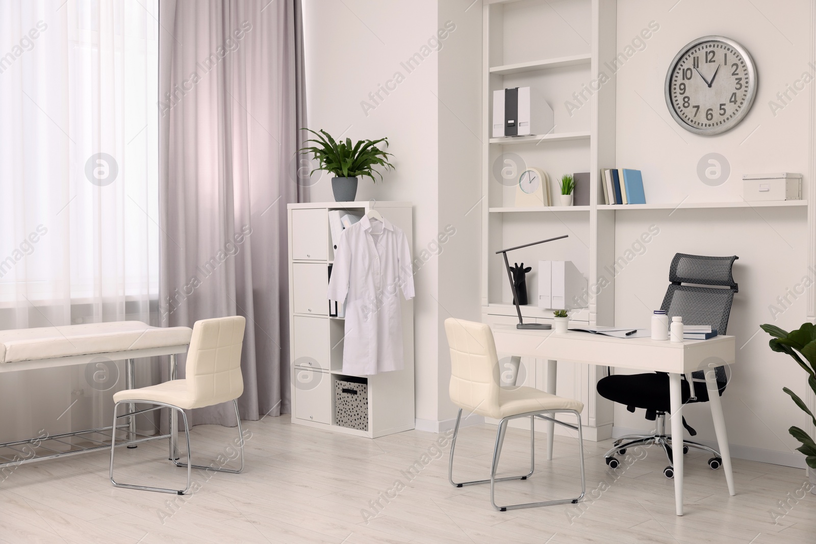 Photo of Modern medical office interior with doctor's workplace and examination table